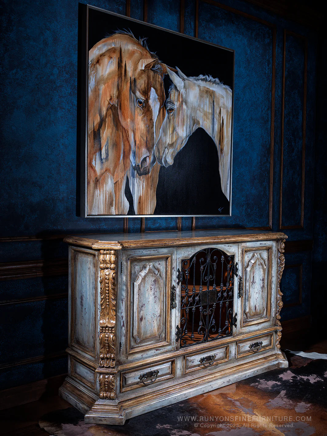 Painting of two horses on a wall above an ornate wooden cabinet.