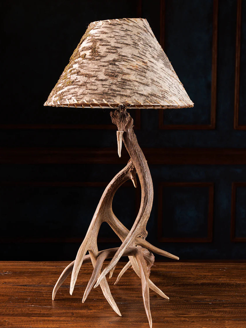 Table lamp with deer antlers and a natural wood shade on a dark background