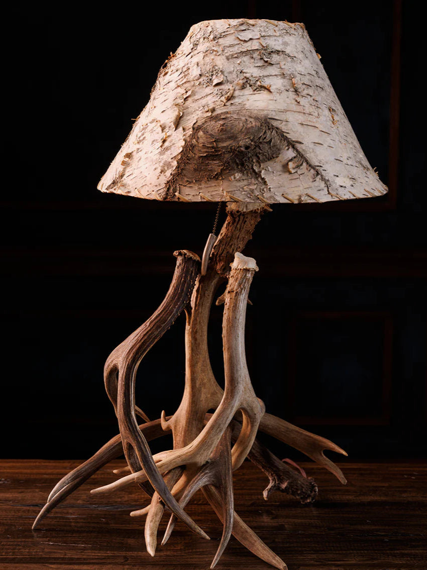 Table lamp with deer antlers and a natural wood shade on a dark background