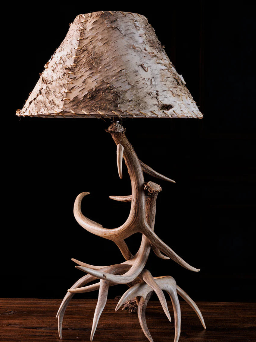 Table lamp with deer antlers and a natural wood shade on a dark background