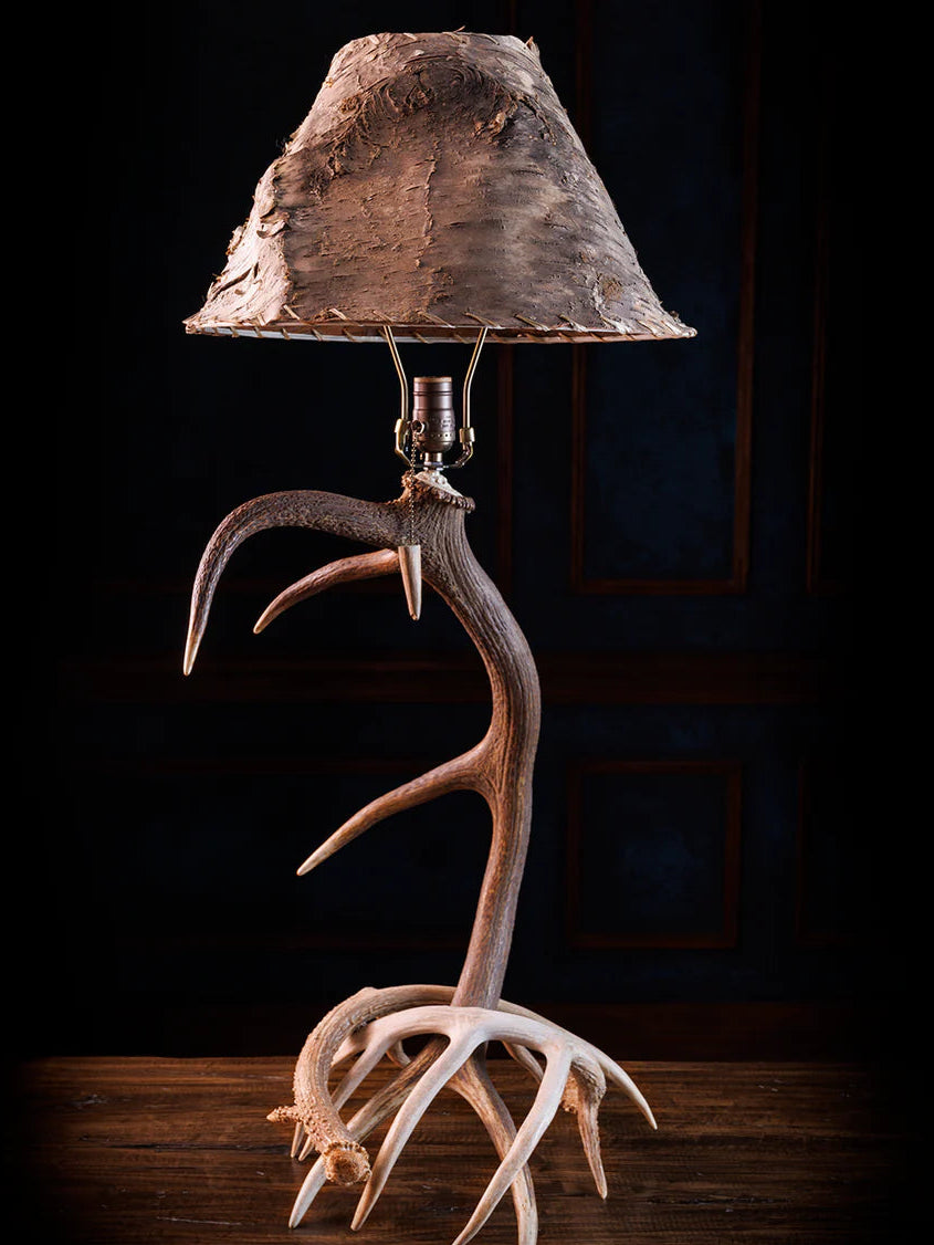 Table lamp with deer antlers and a natural wood shade on a dark background